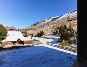A snow-covered landscape with buildings, including a lodge with a sloped roof and solar panels, and a ski lift in the background. - Bright Studio With Cosy Sleeping Corner (Les Deux Alpes)