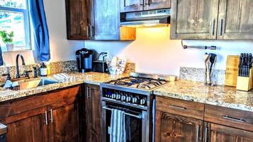 A kitchen with wooden cabinets, a gas stove, a built-in oven, and granite countertops.