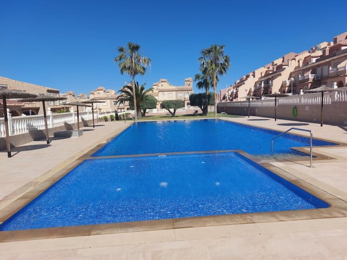 A rectangular swimming pool with a clear blue water surface, surrounded by a tiled deck.