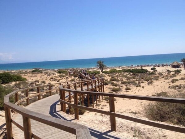 A wooden boardwalk leading to a beach with clear skies. - Casa Helgar in Gran Alacant, Beautiful Sun Set Views & Perfectly Located (Santa Pola)
