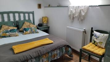 Een slaapkamer met een bed, een stoel, een radiator, een plank en een raam.