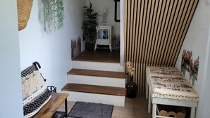 A staircase leading to a room with a white cabinet, a bench, and a hanging plant.