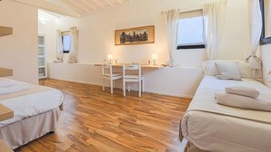 Un dormitorio con dos camas, un escritorio, sillas, un cuadro y una ventana con cortinas.