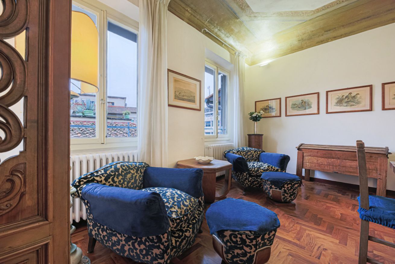 Quarto com piso de madeira, radiador, mesa e cadeiras com estofamento de onça.