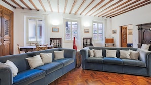 Una habitación con dos sofás azules, vigas de madera en el techo y un suelo con patrón de espiga.