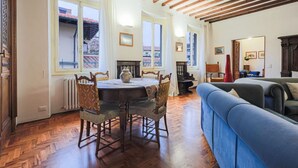 Un comedor con mesa de madera, sillas y vista a través de amplios ventanales.