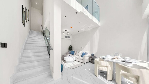 Um interior moderno com uma escadaria, uma sala de jantar e uma sala de estar.