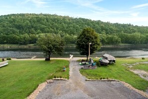 A campsite with a gravel path leading to a picnic table and a covered area with a boat.