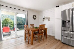 Una cocina moderna con refrigerador empotrado, mesa de comedor de madera y sillas.