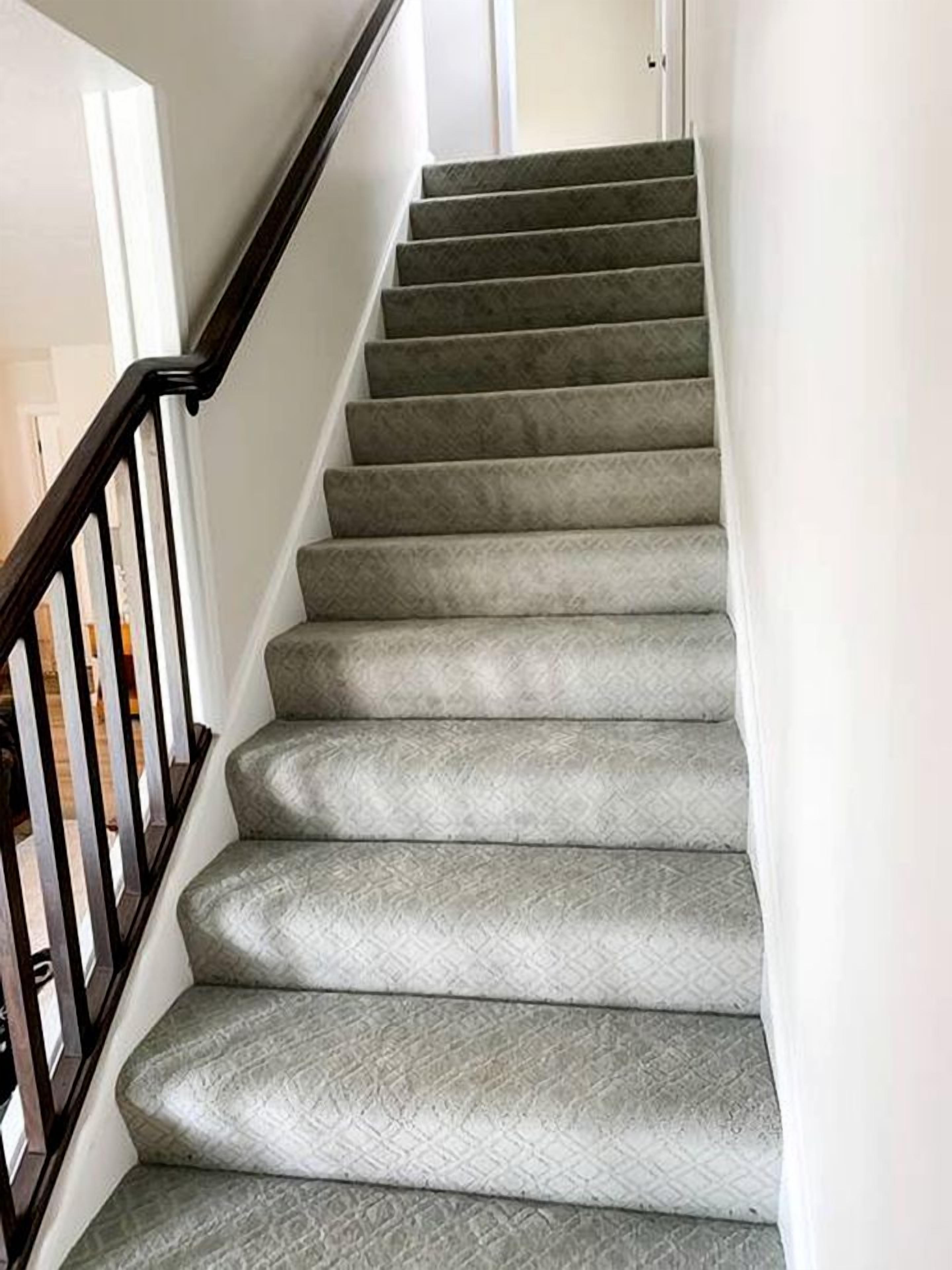 A carpeted staircase with a handrail and a door at the top.