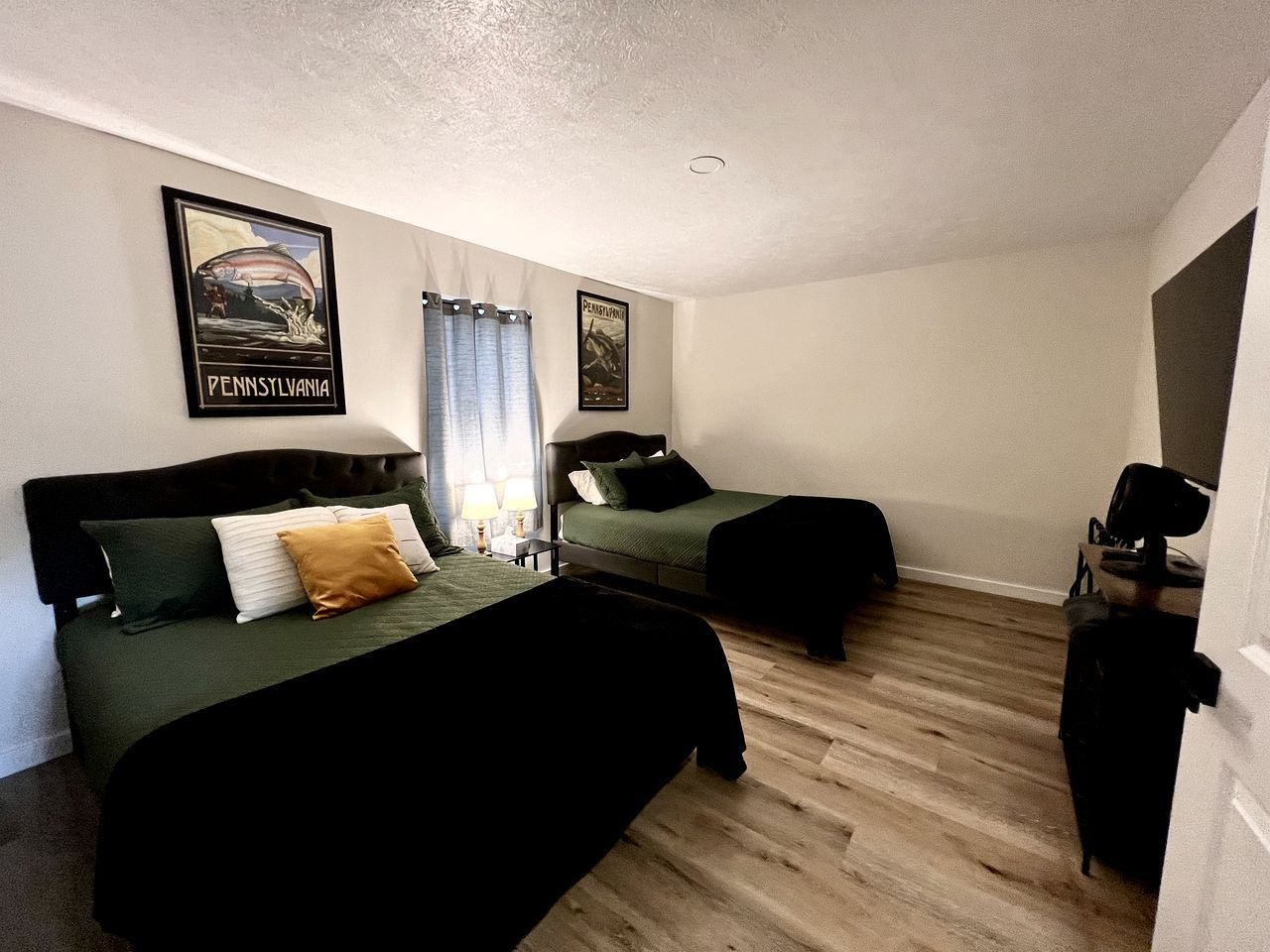 Une chambre d’hôtel avec deux lits, un bureau, une chaise et une armoire.