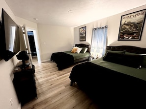 A bedroom with two beds, a mirror, a dresser, and a television.