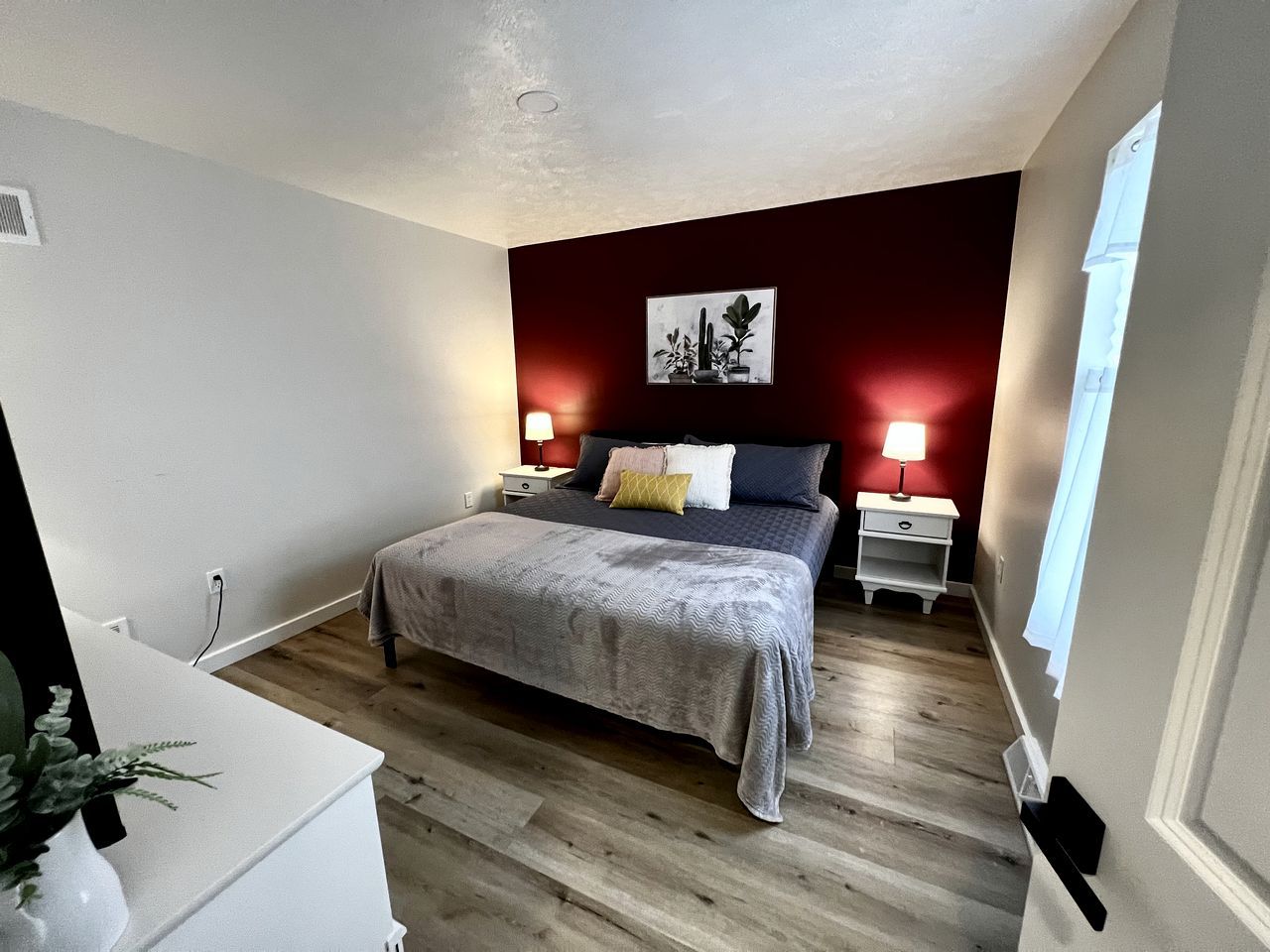 Un dormitorio con cama, mesitas de noche, escritorio y una planta en maceta.
