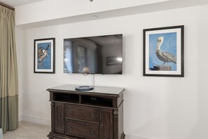 Ein Zimmer mit einem wandmontierten Flachbildfernseher, einem dunklen Holzschrank darunter und zwei gerahmten Bildern an jeder Seite des Fernsehers.