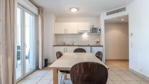 Uma cozinha moderna com armários brancos, micro-ondas e um espaço de jantar com mesa e cadeiras.