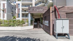 Um edifício com uma placa que diz 'Le Crystal' e uma entrada com portão.
