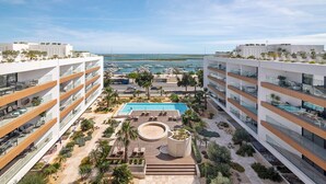 A modern hotel with a rooftop pool, multiple balconies, and a marina view. - Ria Front Paradise – A Gem Facing the Ria (Olhão)