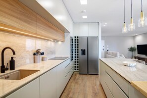 Een moderne keuken met een ingebouwd spoelgedeelte, roestvrijstalen apparatuur en een houten aanrecht.
