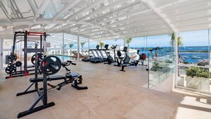 A gym with weightlifting equipment, cardio machines, and a view of the sea. - Ria Front Paradise – A Gem Facing the Ria (Olhão)