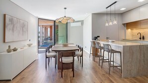 A modern kitchen with a central island, bar stools, and a dining table with chairs. - Ria Front Paradise – A Gem Facing the Ria (Olhão)