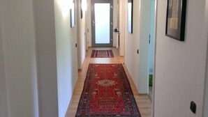 Un pasillo con piso de madera, un tapete rojo y una puerta al final.