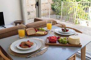 Ein Frühstückstisch mit Pfannkuchen, Toast, Käse und Obst, dazu ein Glas Orangensaft.