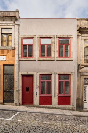 Ein Gebäude mit roter Tür und Fenstern, mit den Hausnummern 154 und 156, vor einer Kopfsteinpflasterstraße.