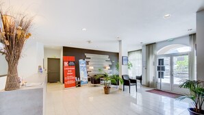 Eine moderne Lobby mit einer Rezeption, einer Sitzecke und großen Fenstern.