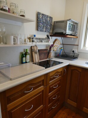 A kitchen with wooden cabinets, a microwave, and various kitchen utensils.