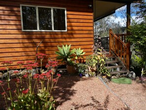 A wooden house with a covered porch, a wooden staircase, and various potted plants.