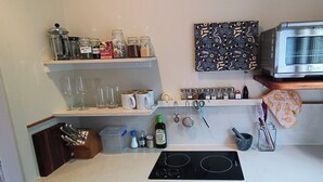 A kitchen with a built-in oven, shelves with jars, a spice rack, and a countertop with a stove.