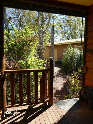 A wooden deck with a view of a garden and a building.