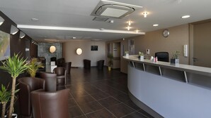 A modern reception area with a curved counter, leather seating, and potted plants. - Montpellier Base Near Coast With Balcony (Saint-Jean-de-Vedas)