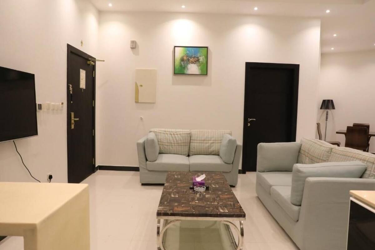 A living room with two sofas, a coffee table, a TV, and a door.