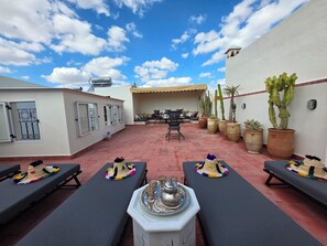 Eine Dachterrasse mit Liegestühlen, einem Essbereich und Sukkulenten in Töpfen.
