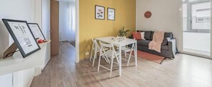 Un salon comprenant une table à manger, un canapé et une grande fenêtre.