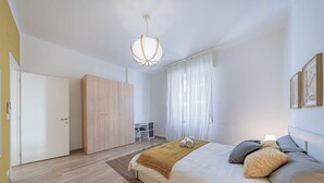 A bedroom with a bed, a wardrobe, a desk, and a chair.