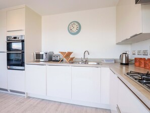 Una cocina moderna con electrodomésticos integrados, un lavamanos y un reloj de pared.