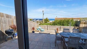 A patio with a table and chairs, a barbecue grill, and a view of the ocean. - Serfaus (Perranporth)