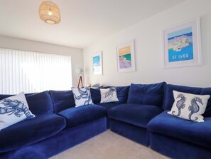 Ein Wohnzimmer mit einem blauen, modularen Sofa, einer Stehlampe und gerahmten Kunstwerken an den Wänden.