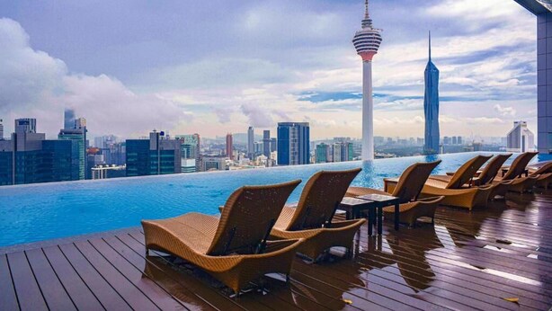 An infinity pool with lounge chairs, a city skyline, and a tower in the background. - kl city center klcc by dome (Kuala Lumpur)