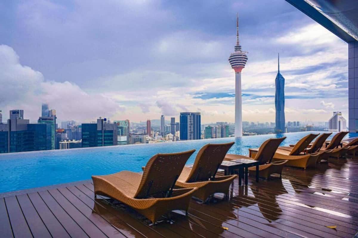 An infinity pool with lounge chairs, a city skyline, and a tower in the background.