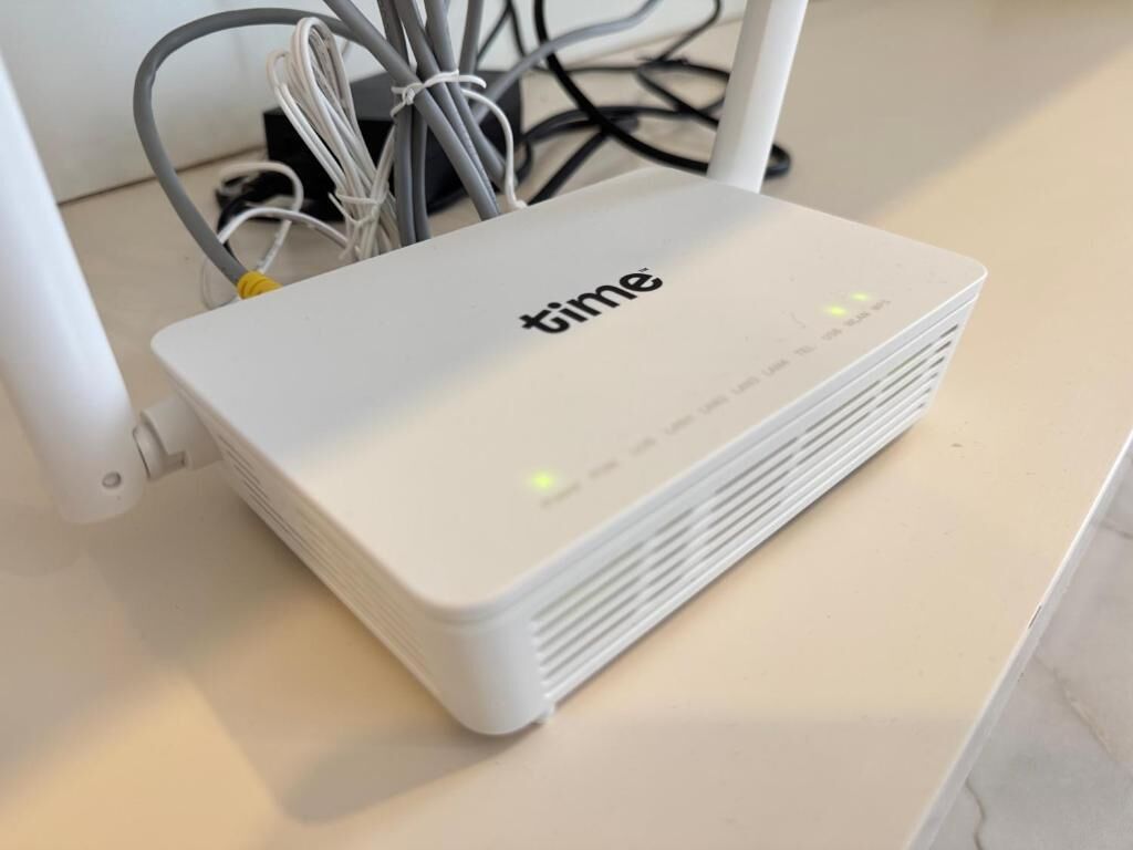 Een wit elektronisch apparaat met het merk 'time' op het bovenste oppervlak, geplaatst op een vlak oppervlak.