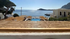 Zona de piscina con vista al mar, una pérgola y un edificio con balcón.