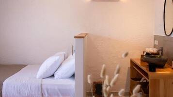 Un dormitorio con una cama, una mesita de noche de madera, una mesa con un florero y un ventilador de techo.