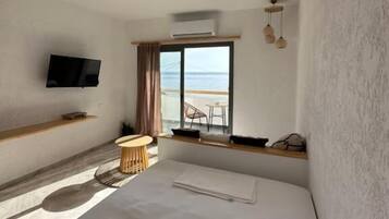 Una habitación de hotel con cama, televisor, ventilador de techo, ventana con vistas y una mesita.