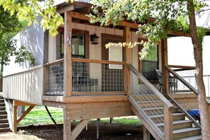 Une terrasse en bois avec une rambarde en métal, un escalier et une porte portant le numéro 16.