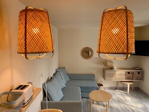 Een moderne woonkamer met een bank, een kleine tafel, een broodrooster en een hanglamp.