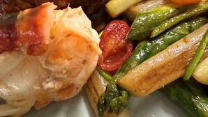 A plate with a grilled steak, roasted potatoes, asparagus, and a shrimp. - Lindenhof Peritz (Wuelknitz)