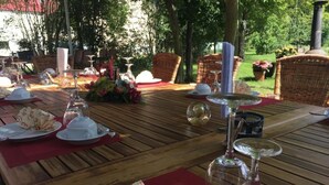 An outdoor dining table set with plates, glasses, and a basket. - Lindenhof Peritz (Wuelknitz)